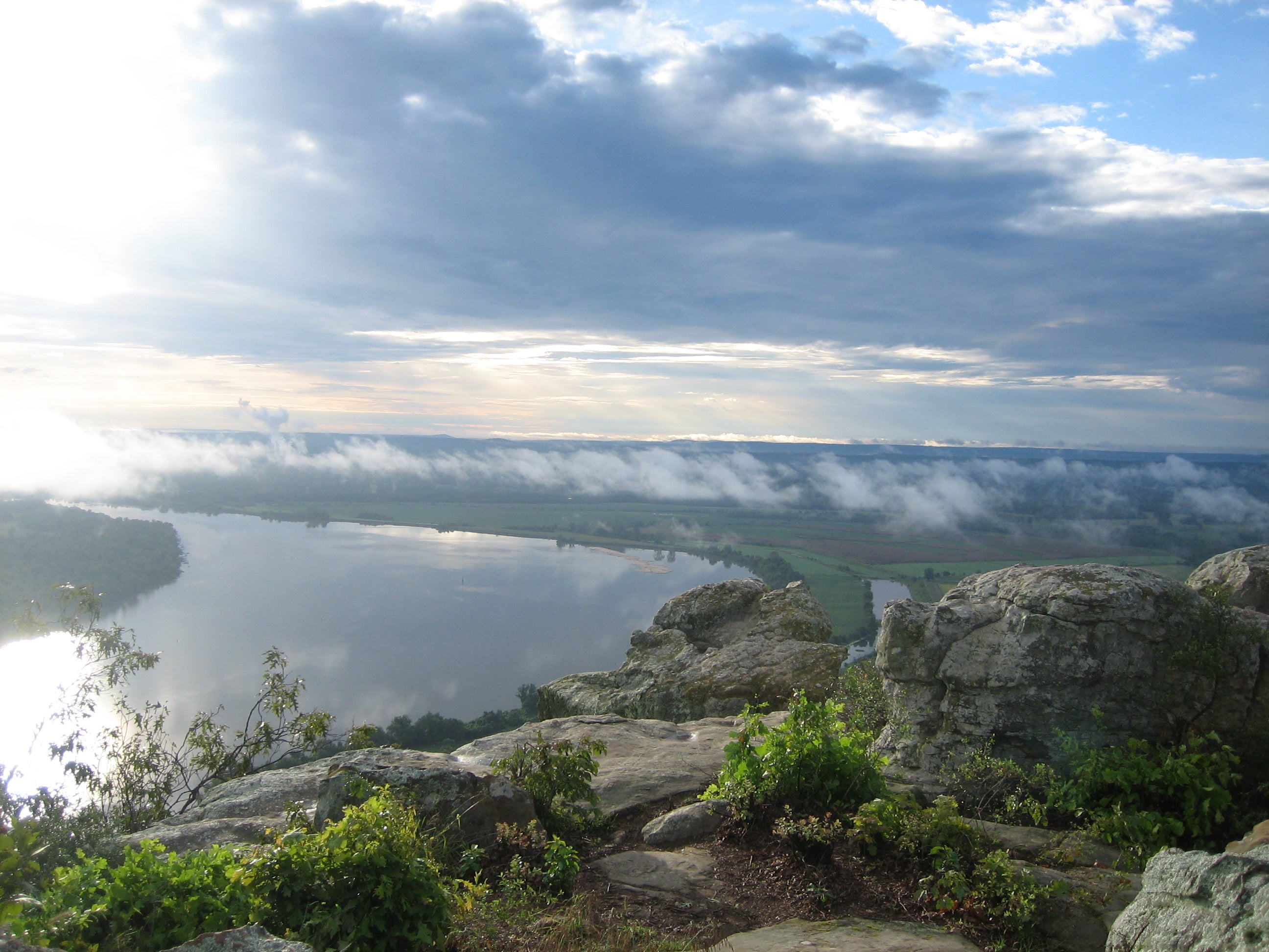 Sun peeking through the clouds shines down on the river as viewed from Petit Jean State Park. Photo Courtesy of Petit Jean State Park